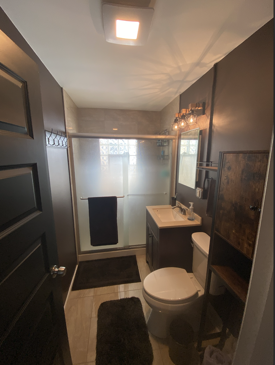 Bathroom renovation project showing new tile flooring, modern vanity, mirror installation and professional tools